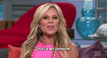 a woman in a pink dress is sitting on a couch and saying `` that 's my opinion ! ''