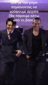two men in suits and ties are standing next to each other in front of a purple background with greek writing on it