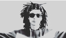 a black and white photo of a man with dreadlocks wearing sunglasses and a bandana