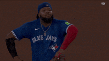 a man wearing a blue jays jersey stands on the field