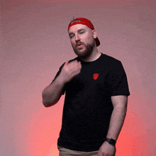 a man with a beard wearing a red hat and a black t-shirt with a red emblem on the left side