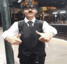 a young man wearing a suit and tie is giving a thumbs up .