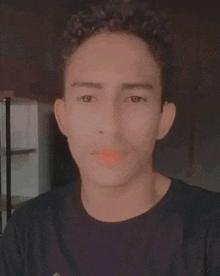 a young man with curly hair is wearing a black shirt and taking a selfie .