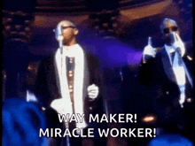 two men in suits singing into microphones with the words way maker miracle worker