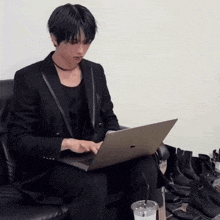 a man in a suit is sitting on a couch using a laptop computer .
