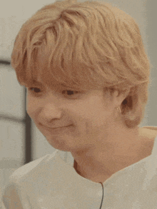 a close up of a person 's face with blonde hair and a white shirt .