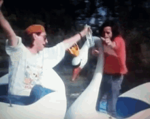 a man in a red shirt is standing next to a swan boat
