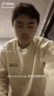 a young man with a mustache is wearing a yellow sweater and making a funny face .