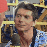 a man is talking into a microphone and smiling while wearing a blue shirt .