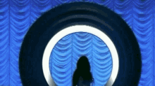 a woman is standing in the middle of a blue curtain