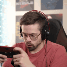 a man wearing glasses and headphones is playing a game on his phone