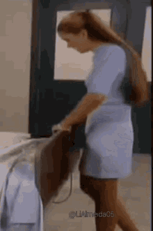 a woman in a blue dress is standing in a hallway holding a suitcase .