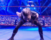 a wrestler is kneeling down in a wrestling ring with his legs crossed .