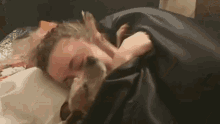 a woman is sleeping in bed with a dog .