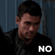 a man in a leather jacket is standing in front of a no sign