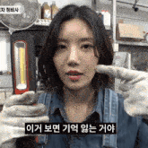 a woman wearing overalls and gloves is holding a flashlight and pointing at it in a foreign language