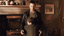 a man in a leather jacket is hugging a little boy