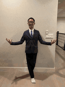 a young man in a suit and tie is standing in front of a wall with a remote control on it
