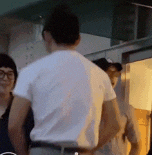 a man in a white shirt is standing next to a woman in glasses