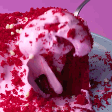 a slice of red velvet cake with pink frosting and crumbs