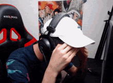 a man wearing headphones and a hat with the word dxr on the back of his chair