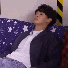 a man in a suit is sitting on a couch with a star blanket .