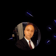 a man in a suit and tie stands in front of a sign that says yosun gozleri