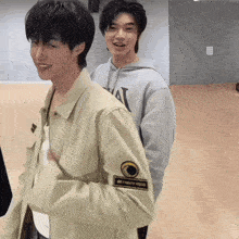 a man wearing a hoodie with the letter n on it stands next to another man