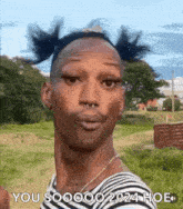 a man with pigtails on his head is standing in a field .
