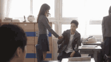 a girl shakes a man 's hand in a classroom