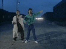 a couple of people are dancing on a street at night