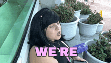 a woman is sleeping in front of potted plants and a sign that says we 're in pink