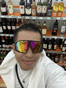 a man wearing sunglasses stands in front of a shelf full of alcohol including jack daniels