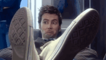 a man is sitting with his feet up and his converse shoes on