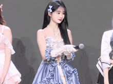 a woman in a blue dress holds a microphone
