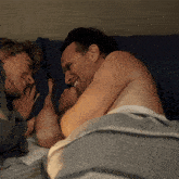 a man and a woman are laying on a bed and the man is smiling