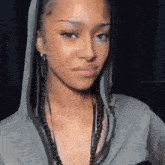 a close up of a woman wearing a hoodie and braids