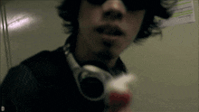 a man wearing headphones and sunglasses is holding a bottle of toothpaste