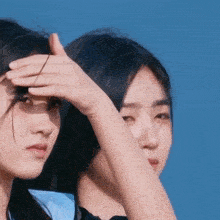 a woman covering her face with her hand while another woman looks at her
