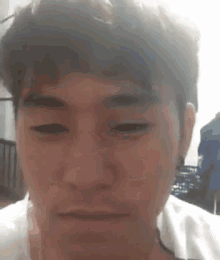 a close up of a man 's face with his eyes closed and a white shirt on .
