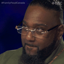 a man with glasses and a beard is on a tv show called familyfeud canada