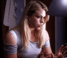 a woman with long blonde hair is wearing earrings and a gray shirt