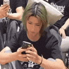 a man with green hair is using a cell phone .