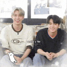 two men are sitting next to each other on a couch and smiling .