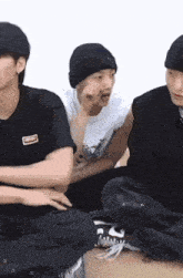 a man wearing a black beanie is sitting next to two other men