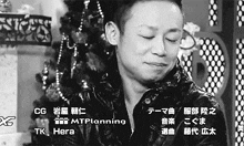 a black and white photo of a man in front of a christmas tree with the words tk hera at the bottom