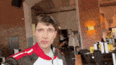 a man in a red and white jacket is taking a selfie in front of a brick wall