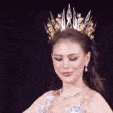a woman wearing a tiara and a necklace looks down