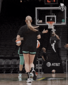 a female basketball player runs towards a hoop with an at & t sign in the background