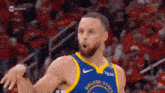a basketball player in a golden state warriors uniform is standing on the court .